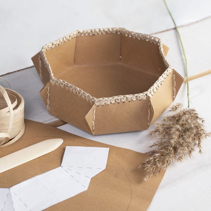 A faux leather paper basket with a crocheted raffia paper yarn edge