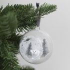 A Christmas bauble with a hole at the front decorated with artificial snow and mini figures 