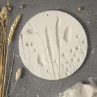 A plate from self-hardening clay with imprints of dried flowers