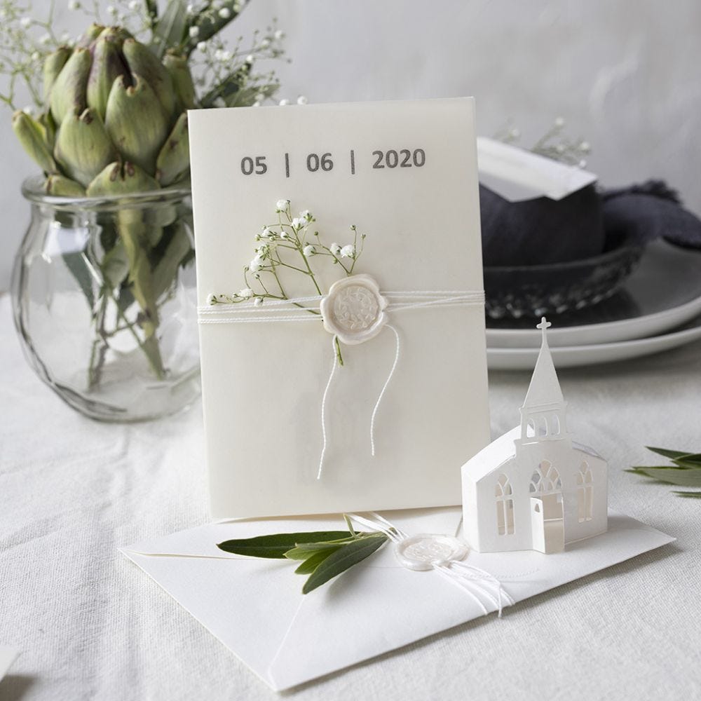 An invitation in off-white shades with a punched-out church and vellum paper