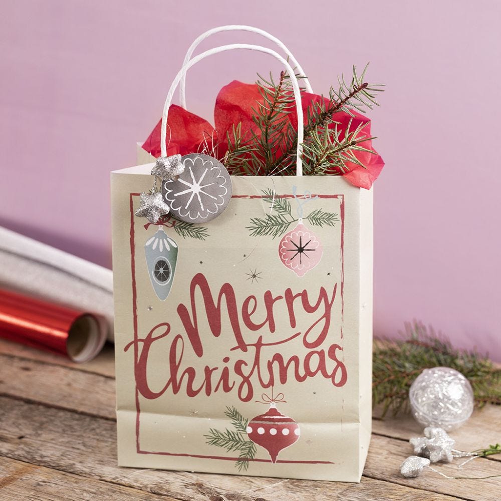 A gift bag with a Christmas design, decorated with a star, lametta and tissue paper